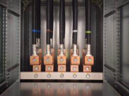 Vijf dikke elektrische kabels aangesloten op koperen klemmen in een metalen elektrisch paneel.