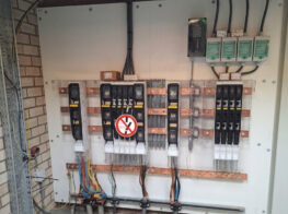 Een elektrisch paneel met meerdere stroomonderbrekers, bedrading en een waarschuwingsbord 