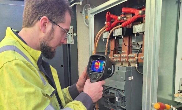 thermografische-scan Een technicus van NED gebruikt een warmtebeeldcamera om elektrische onderdelen in een open bedieningspaneel te inspecteren.
